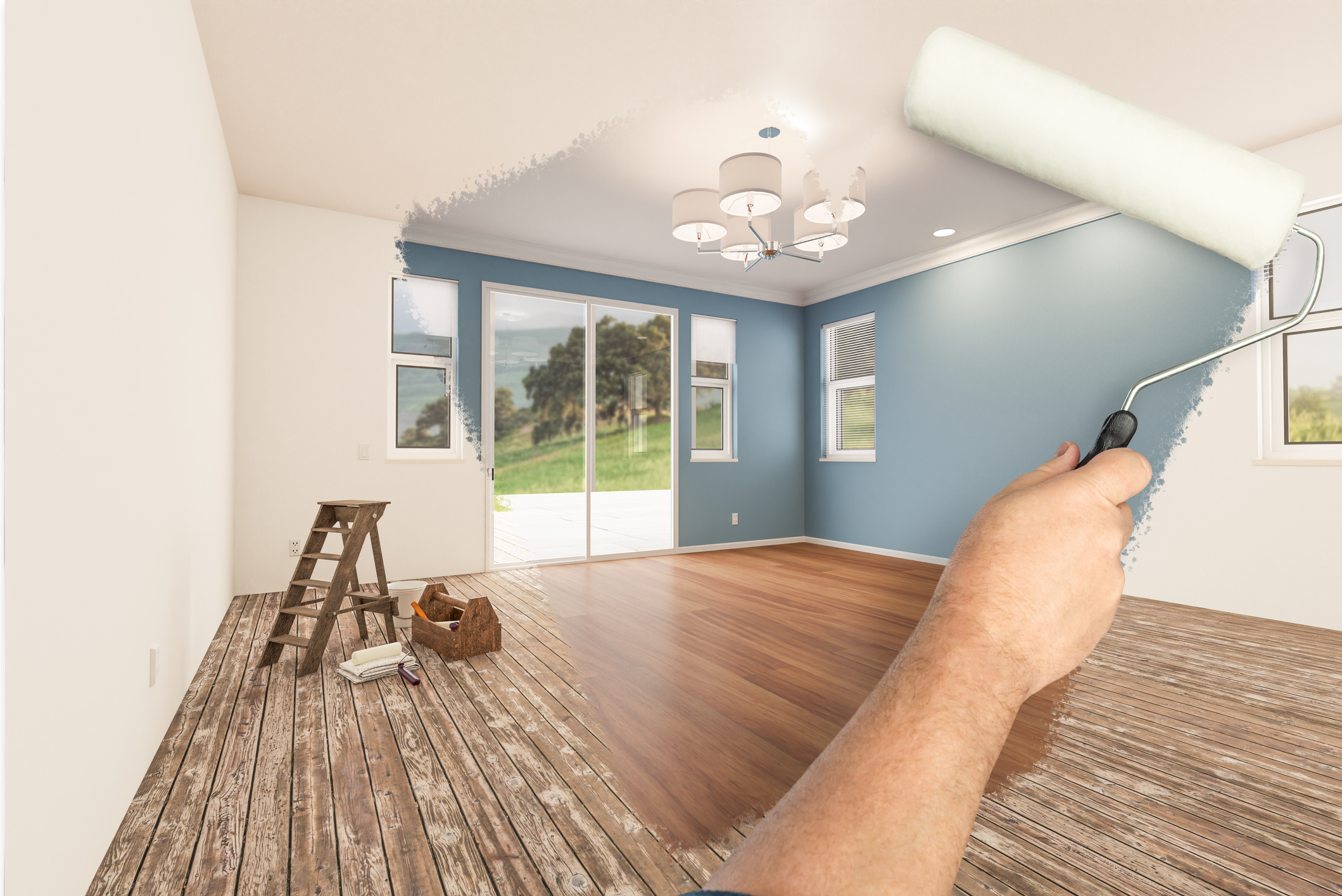 Before and After of Man Painting Roller to Reveal Newly Remodeled Room with Fresh Blue Paint and New Floors.